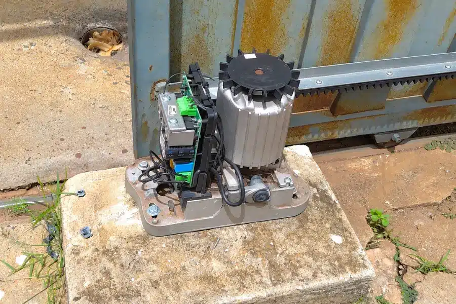 Motor de portão deslizante sem a tampa, com placa eletrônica e cremalheira visíveis